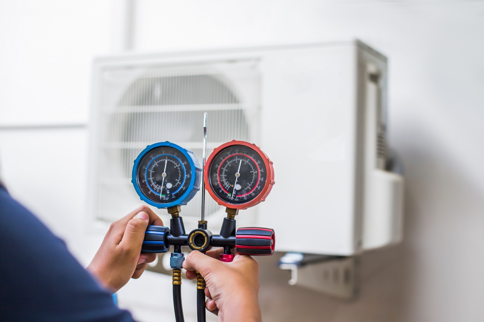 Technician checking gauges in front of an outdoor air conditioner